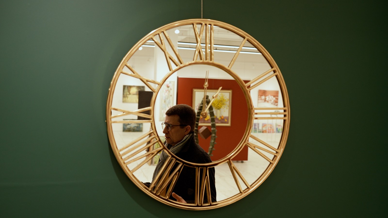 Un visitatore osserva un dipinto in una sala espositiva.
