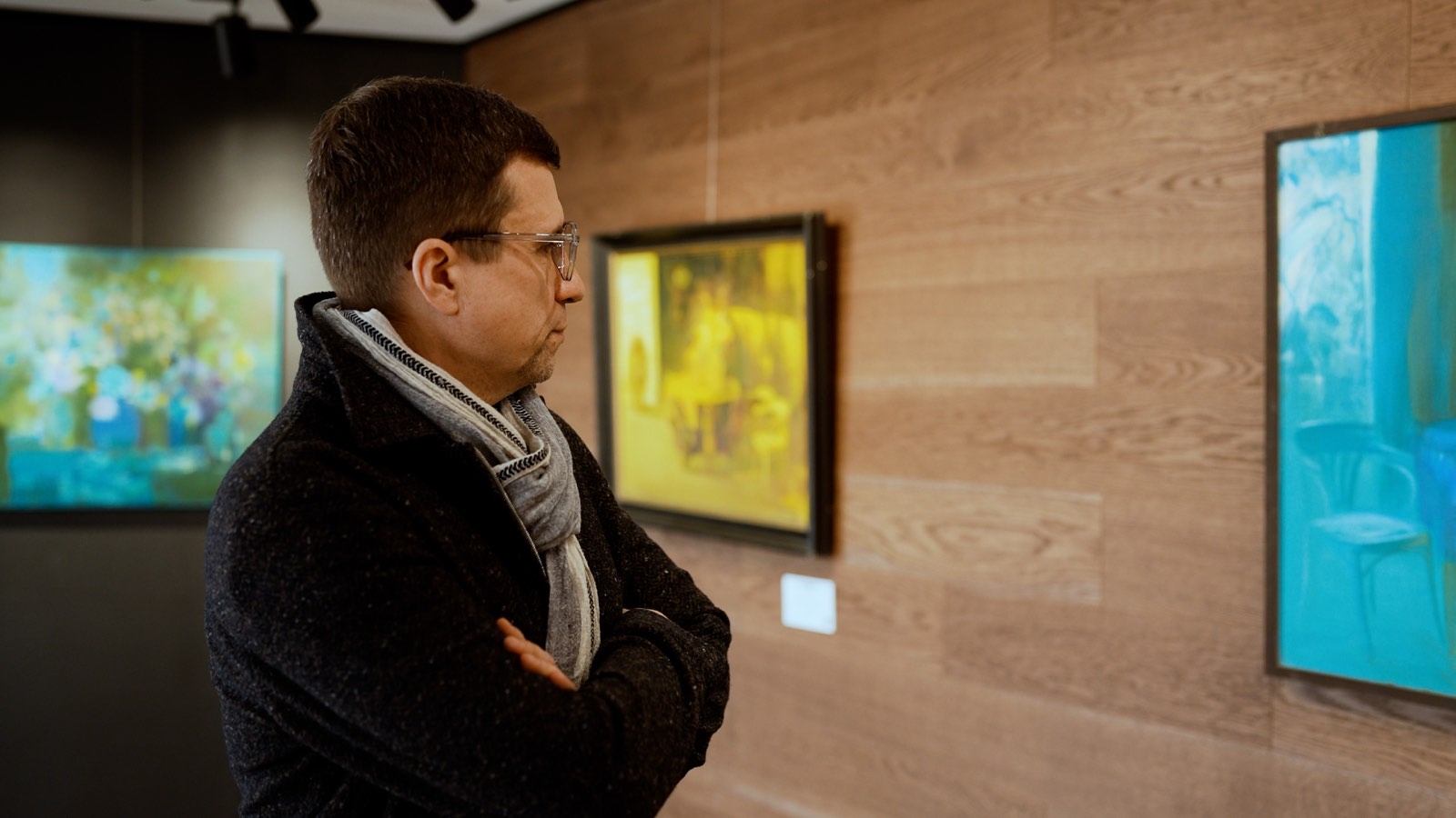 Un visitatore davanti ai dipinti in uno spazio espositivo.