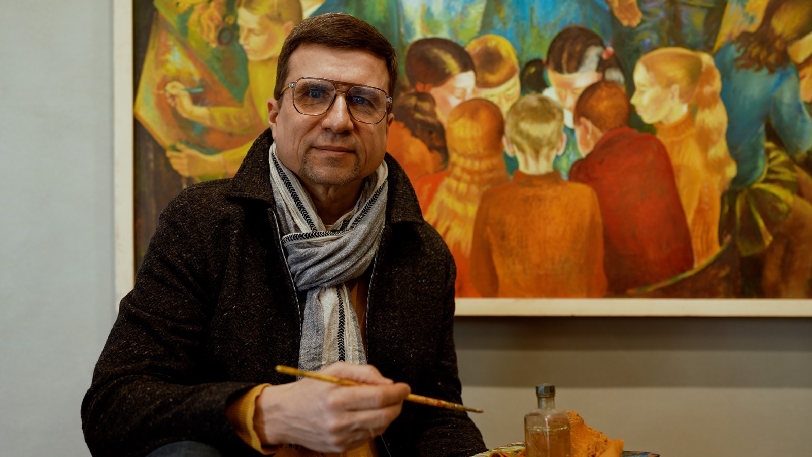 Un visitatore osserva attentamente un dipinto.